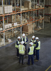 Manager and workers meeting in circle in distribution warehouse - HOXF02842