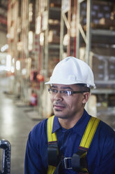 Arbeiter mit Schutzhelm schaut in einem Auslieferungslager weg - HOXF02844