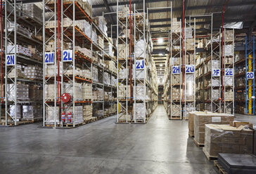 Merchandise stacked on shelves in labeled aisles in distribution warehouse - HOXF02854