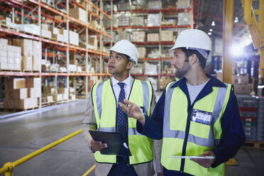 Manger and worker with clipboard and digital tablet talking in distribution warehouse - HOXF02870