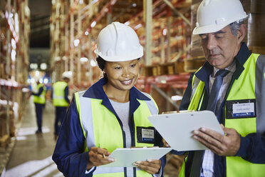 Manager and worker with clipboards meeting in distribution warehouse - HOXF02879