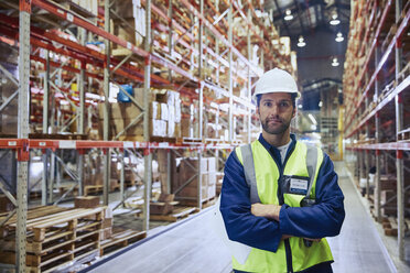 Portrait confident worker with arms crossed in distribution warehouse - HOXF02880