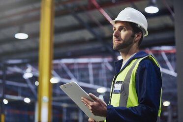 Worker with clipboard looking up in distribution warehouse - HOXF02881