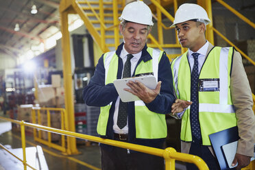 Managers with clipboard meeting talking in distribution warehouse - HOXF02882