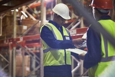 Workers with clipboards meeting in distribution warehouse - HOXF02892