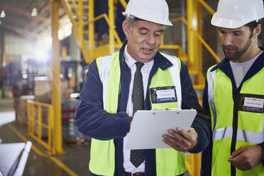 Manager and worker with clipboard meeting in distribution warehouse - HOXF02905