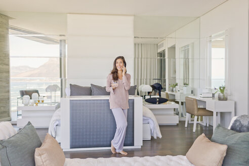 Frau im Gespräch auf dem Handy in modernen Luxus nach Hause Showcase Schlafzimmer - HOXF02914