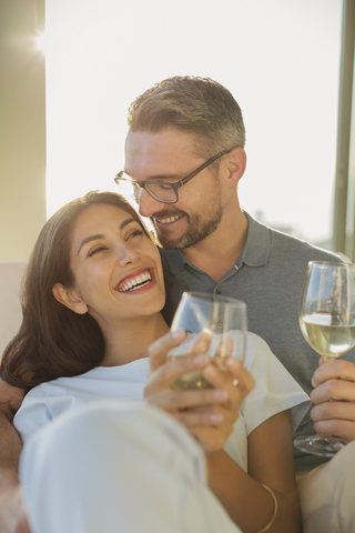 Verliebtes Paar lächelt und trinkt Weißwein, lizenzfreies Stockfoto