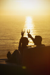 Silhouette Paar Toasting Weingläser auf Balkon mit ruhigen Sonnenuntergang Meerblick - HOXF02929