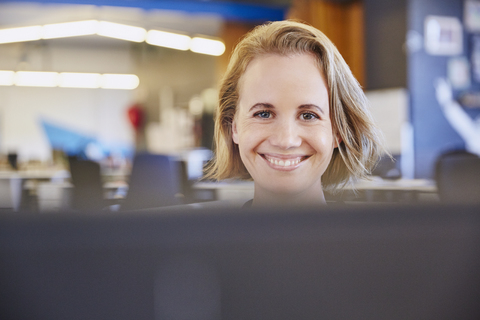 Porträt einer lächelnden Geschäftsfrau bei der Arbeit am Computer, lizenzfreies Stockfoto