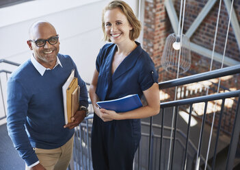 Portrait smiling businessman and businesswoman in stairway - HOXF02971