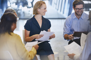 Smiling business people discussing paperwork in meeting - HOXF03042