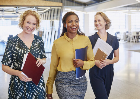 Lächelnde Geschäftsfrauen beim Gang ins Büro - HOXF03052