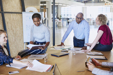 Business people discussing paperwork in conference room meeting - HOXF03053