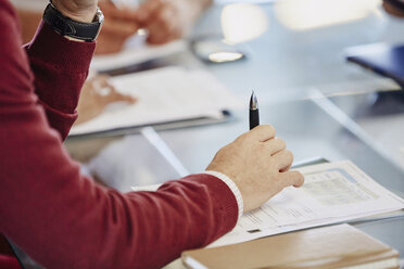 Geschäftsmann mit Papierkram im Meeting - HOXF03054