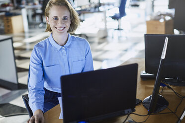 Porträt lächelnde Geschäftsfrau arbeitet am Laptop im Büro - HOXF03068