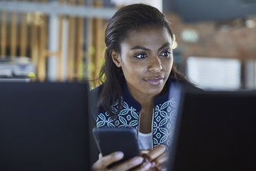 Geschäftsfrau, die am Computer im Büro eine SMS schreibt - HOXF03086