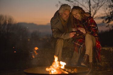Couple drinking enjoying autumn campfire - HOXF03091