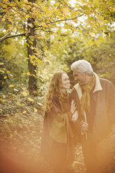 Zärtliches Paar spaziert Arm in Arm im Herbstwald - HOXF03096