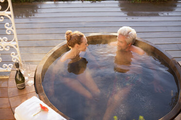 Ein Paar badet im Whirlpool und trinkt Champagner auf der Terrasse - HOXF03107