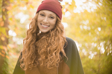 Portrait smiling woman in stocking cap under autumn trees - HOXF03108