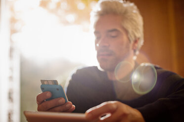 Mann mit Kreditkarte und digitalem Tablet und Smartphone - HOXF03128