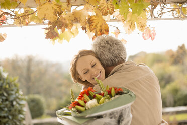 Ehemann überrascht Frau mit Blumenstrauß auf Herbstterrasse - HOXF03137