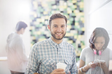 Portrait confident creative businessman drinking coffee in office - HOXF03161