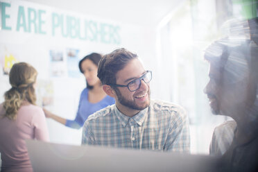 Publishers talking in sunny office - HOXF03170