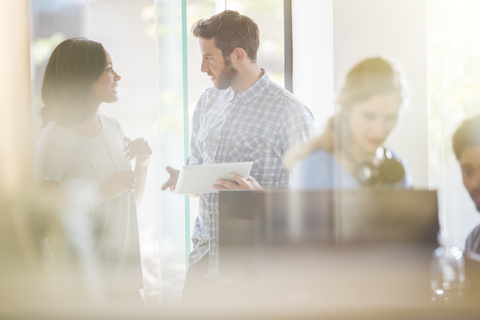 Business people with digital tablet talking in office stock photo