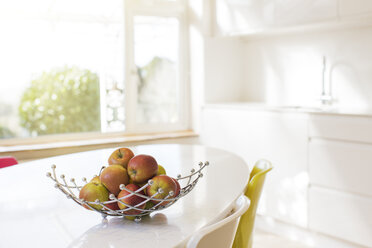 Apples in wire basket on modern kitchen table - HOXF03191