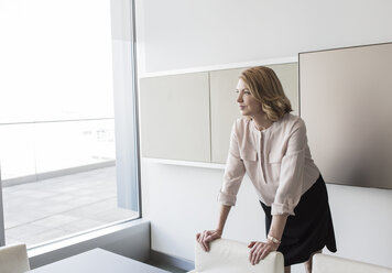 Pensive businesswoman looking out office window - HOXF03200