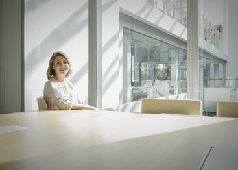 Porträt lächelnde Geschäftsfrau in sonnigem Konferenzraum - HOXF03212