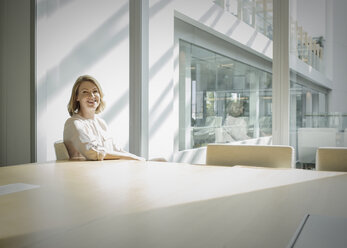 Portrait smiling businesswoman in sunny conference room - HOXF03212