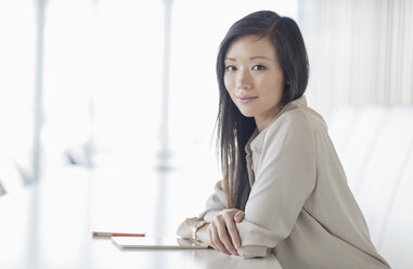 Portrait smiling businesswoman with digital tablet in conference room - HOXF03215