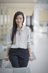 Portrait confident businesswoman leaning on desk - HOXF03218