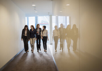 Geschäftsfrauen gehen in einer Reihe im Büroflur - HOXF03236