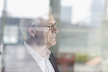 Pensive senior businessman looking out office window - HOXF03238