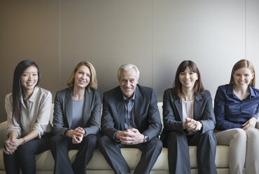 Porträt lächelnde Geschäftsleute in einer Reihe auf Sofa - HOXF03240