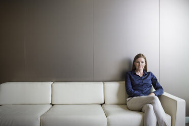 Porträt einer selbstbewussten Geschäftsfrau mit gekreuzten Beinen auf dem Sofa - HOXF03244