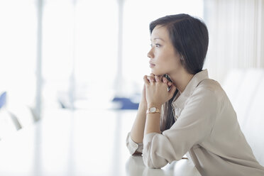 Pensive businesswoman looking away in conference room - HOXF03246