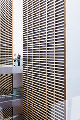 Geschäftsleute im Gespräch auf dem Gehweg in einem modernen Büro-Atrium - HOXF03263