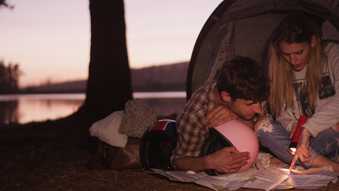 Junges Paar betrachtet Karten im Campingzelt, lizenzfreies Stockfoto