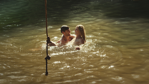 Junges Paar schwimmt im sonnigen See, lizenzfreies Stockfoto