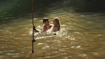 Junges Paar schwimmt im sonnigen See - HOXF03318