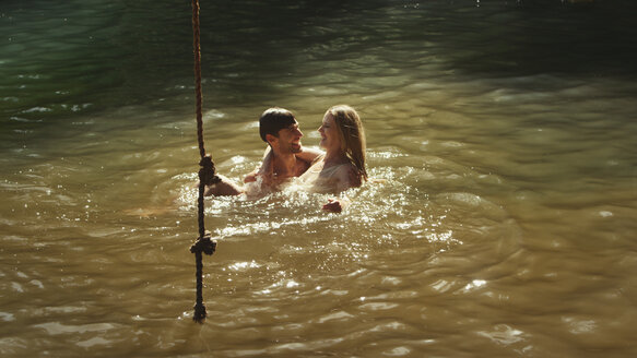 Junges Paar schwimmt im sonnigen See - HOXF03318