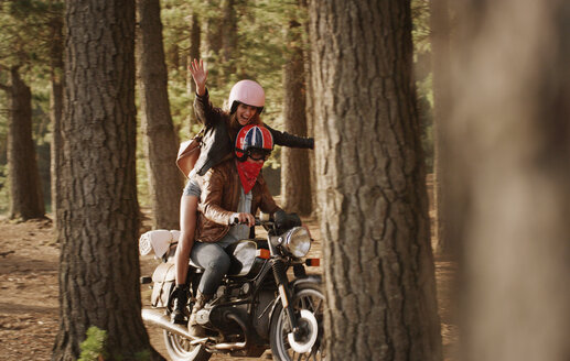 Übermütige junge Frau beim Motorradfahren im Wald - HOXF03323