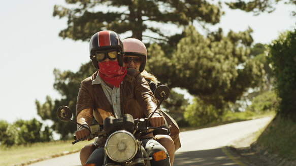 Junges Paar fährt Motorrad auf sonniger Straße - HOXF03332