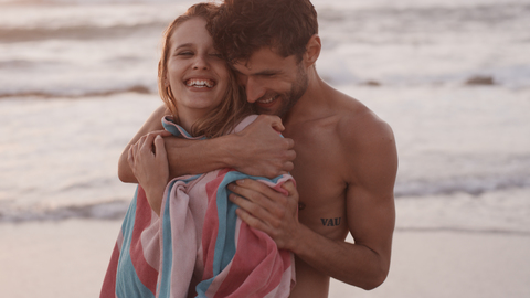 Zärtliches junges Paar, das sich am Strand umarmt, lizenzfreies Stockfoto