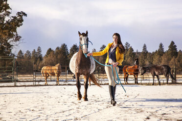 Confident woman walking with horse on snow covered field - CAVF00007